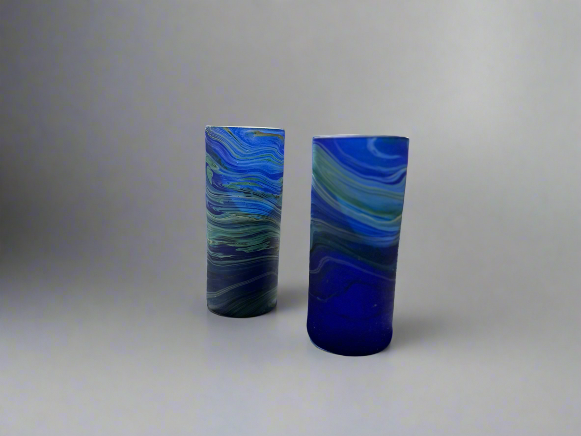 Two handblown Hebron Phoenician glass tumblers with a cobalt blue color, displayed against a neutral background.