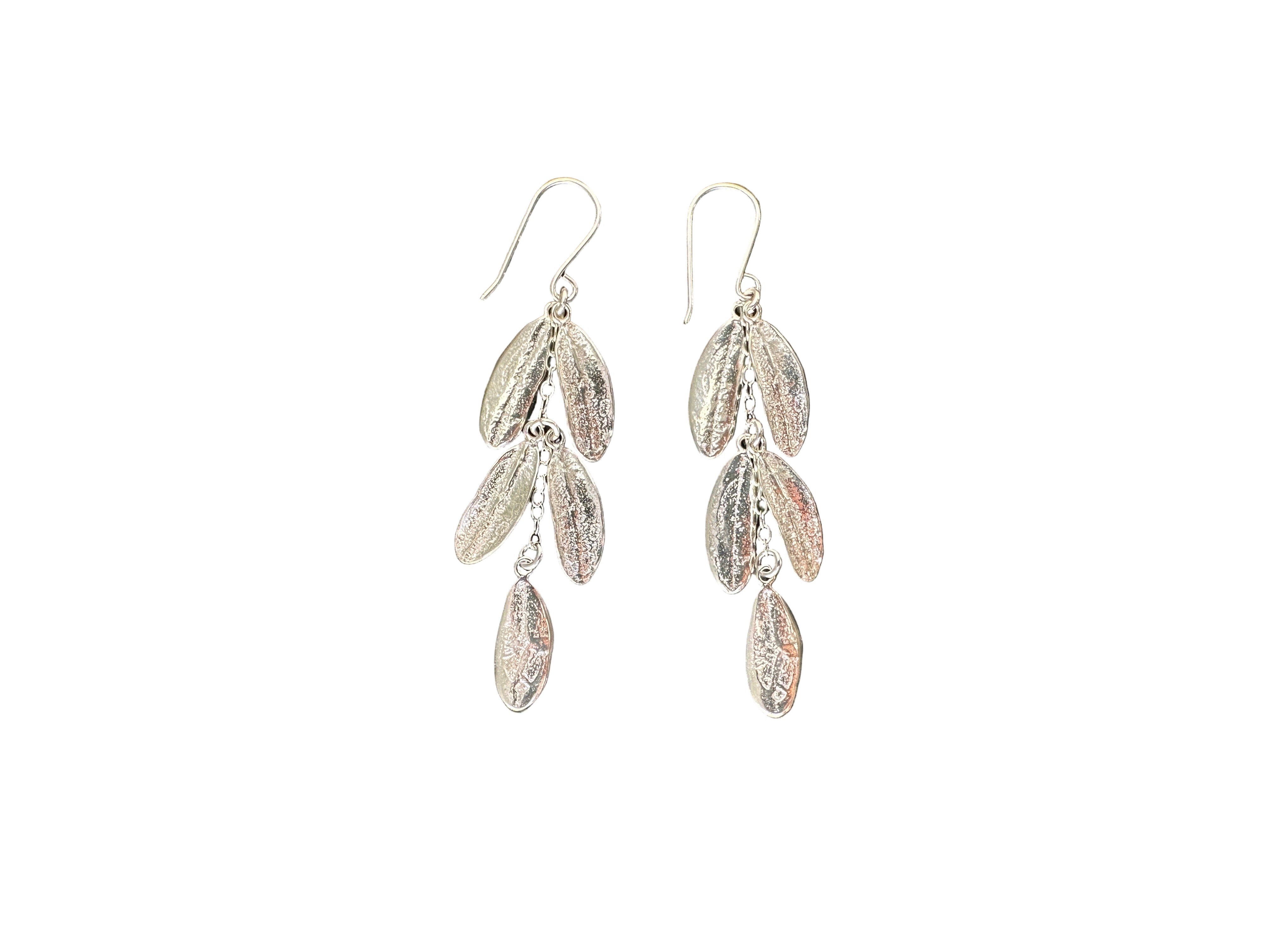 Silver leaf-shaped earrings on a dark stone surface